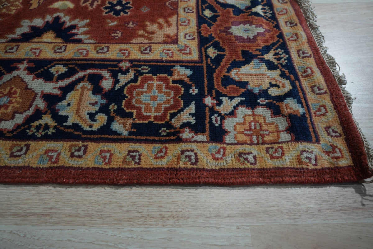 Kira Zinnia Rust Hand Knotted Wool Rug, a vibrant red wool rug with intricate hand-knotted detailing, displayed in a warm, inviting interior setting.