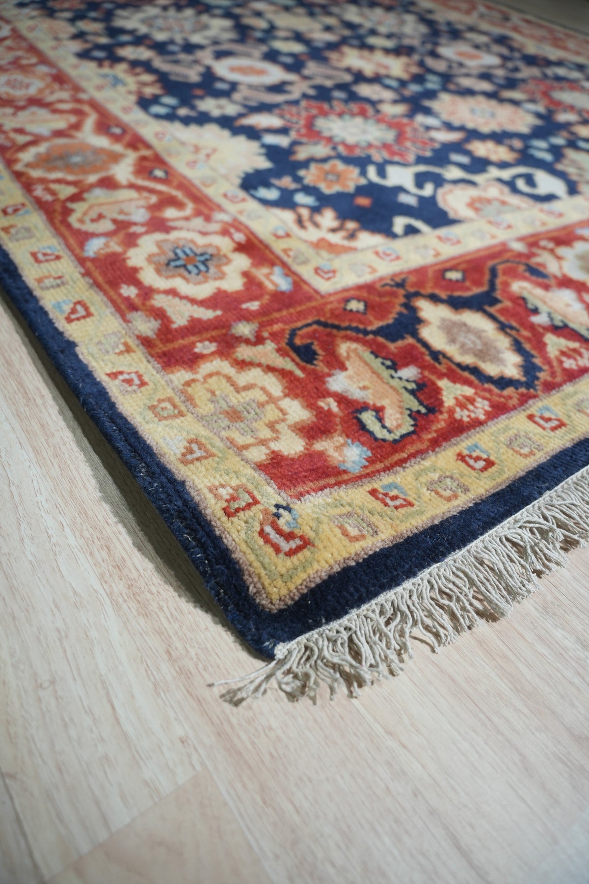 Violet Exquisite Navy Hand Knotted Wool Rug, displaying intricate patterns in deep navy and subtle cream hues, lays gracefully in a brightly lit living room setting.