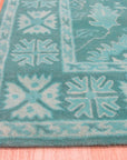 Louie Oriental Turquoise Hand Tufted Wool Rug displayed in a warm, inviting living room setting. Its intricate oriental design, hand-tufted in turquoise wool, adds a vibrant touch to the space.