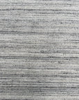 Delicate Striped Silver Handmade Wool Rug displayed in a bright room, its subtle silver stripes catching the light and showcasing the soft wool texture.