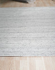 Delicate Striped Silver Handmade Wool Rug, its subtle silver stripes adding a touch of refined texture, captured within a bright, modern interior.