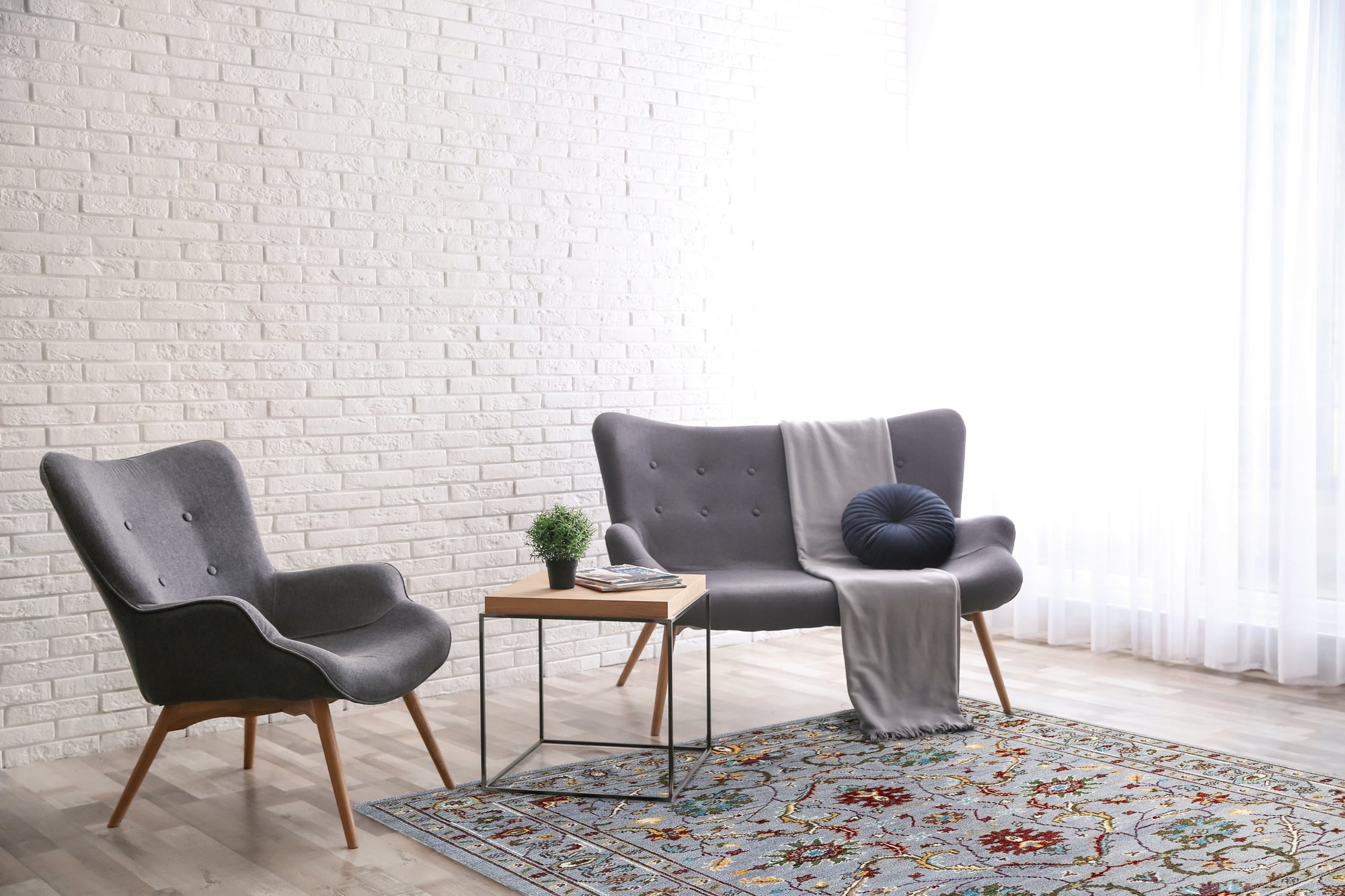 Dahlia Oriental Gray Hand Knotted Wool Rug displayed on a polished hardwood floor. Delicate floral motifs in shades of gray and cream dance across the hand-knotted wool surface, adding subtle elegance to the neutral backdrop.