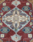 Sophie Chic Red Hand Knotted Wool Rug, showcasing intricate floral patterns woven in vibrant reds and subtle creams, creates a luxurious focal point in a warmly lit room.