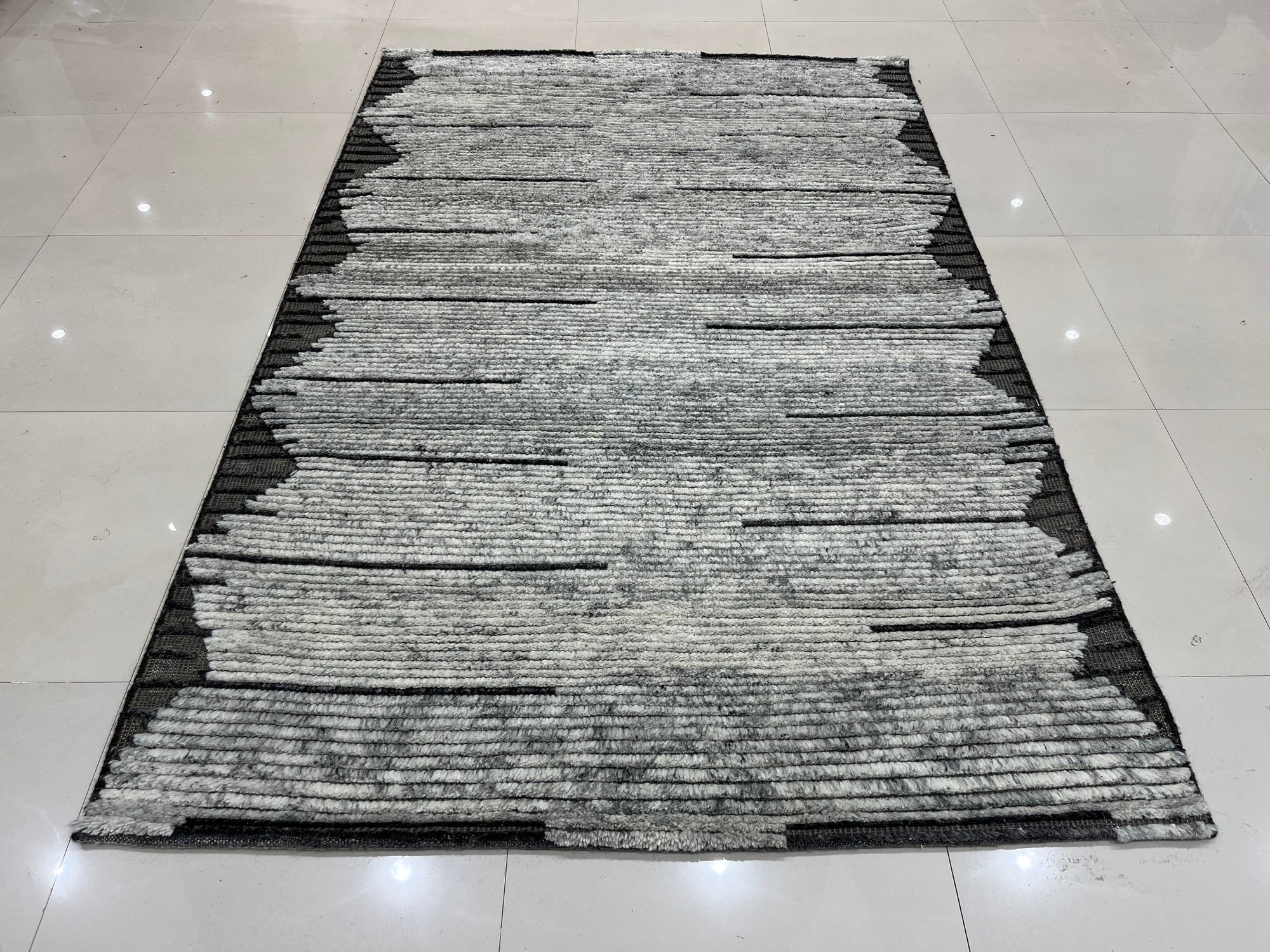 Amara Majestic Gray Hand Knotted Wool Rug, showcasing its intricate hand-knotted construction and sophisticated gray tones, laying gracefully on a light wooden floor.