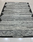 Amara Majestic Gray Hand Knotted Wool Rug, showcasing its intricate hand-knotted construction and sophisticated gray tones, laying gracefully on a light wooden floor.