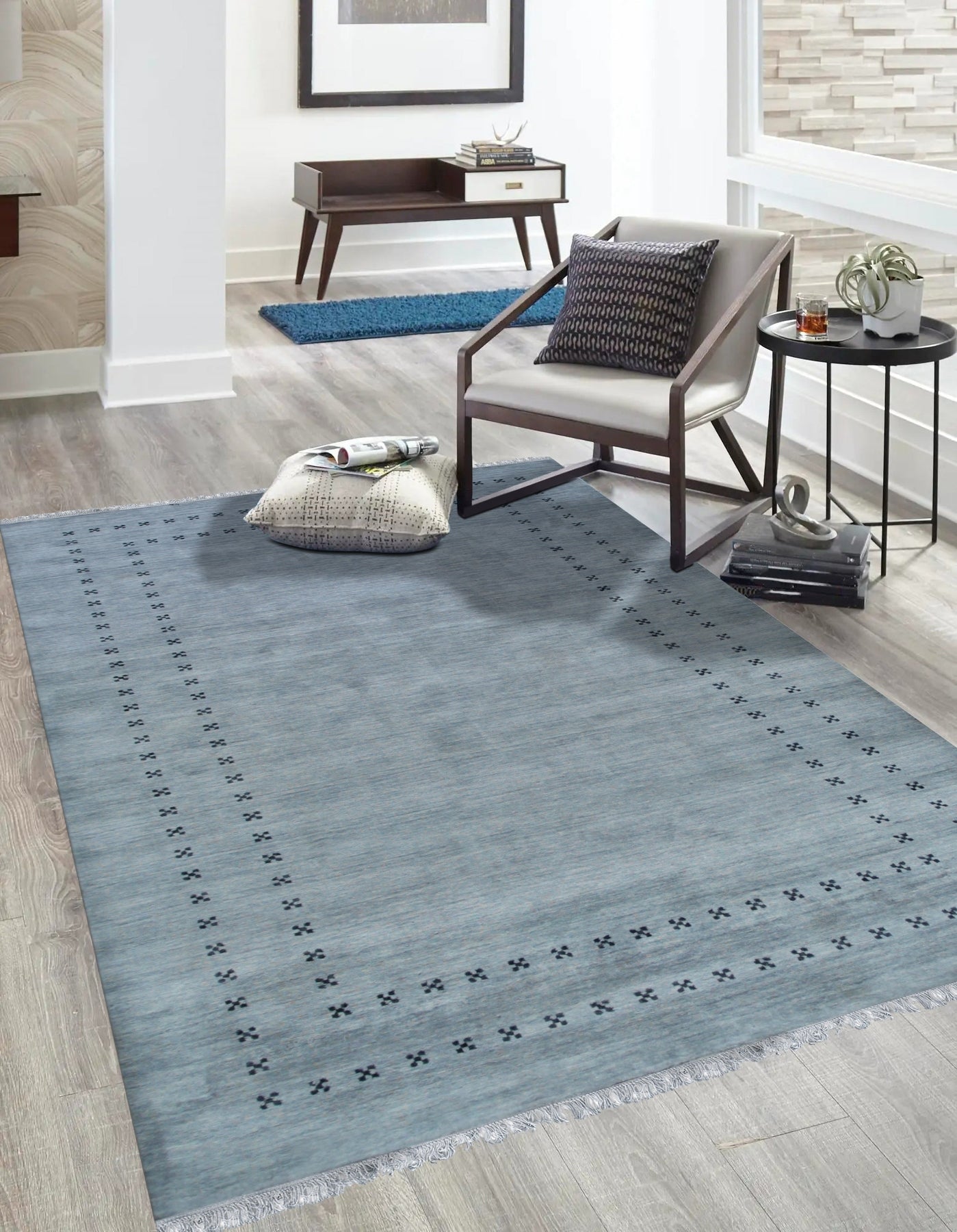 Jasmine Alluring Gray Handmade Wool Rug graces a modern living room; its soft gray tones complementing a white sofa and light wood flooring, creating a serene and inviting atmosphere.