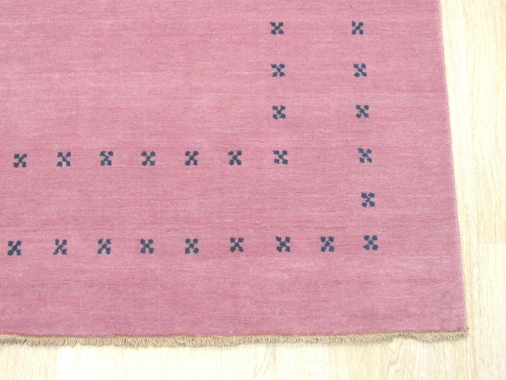 Jasmine Alluring Pink Handmade Wool Rug displayed in a warmly lit living room; soft pink tones and subtle patterns add an elegant touch to the space, complementing the neutral furniture and creating a cozy, inviting atmosphere.