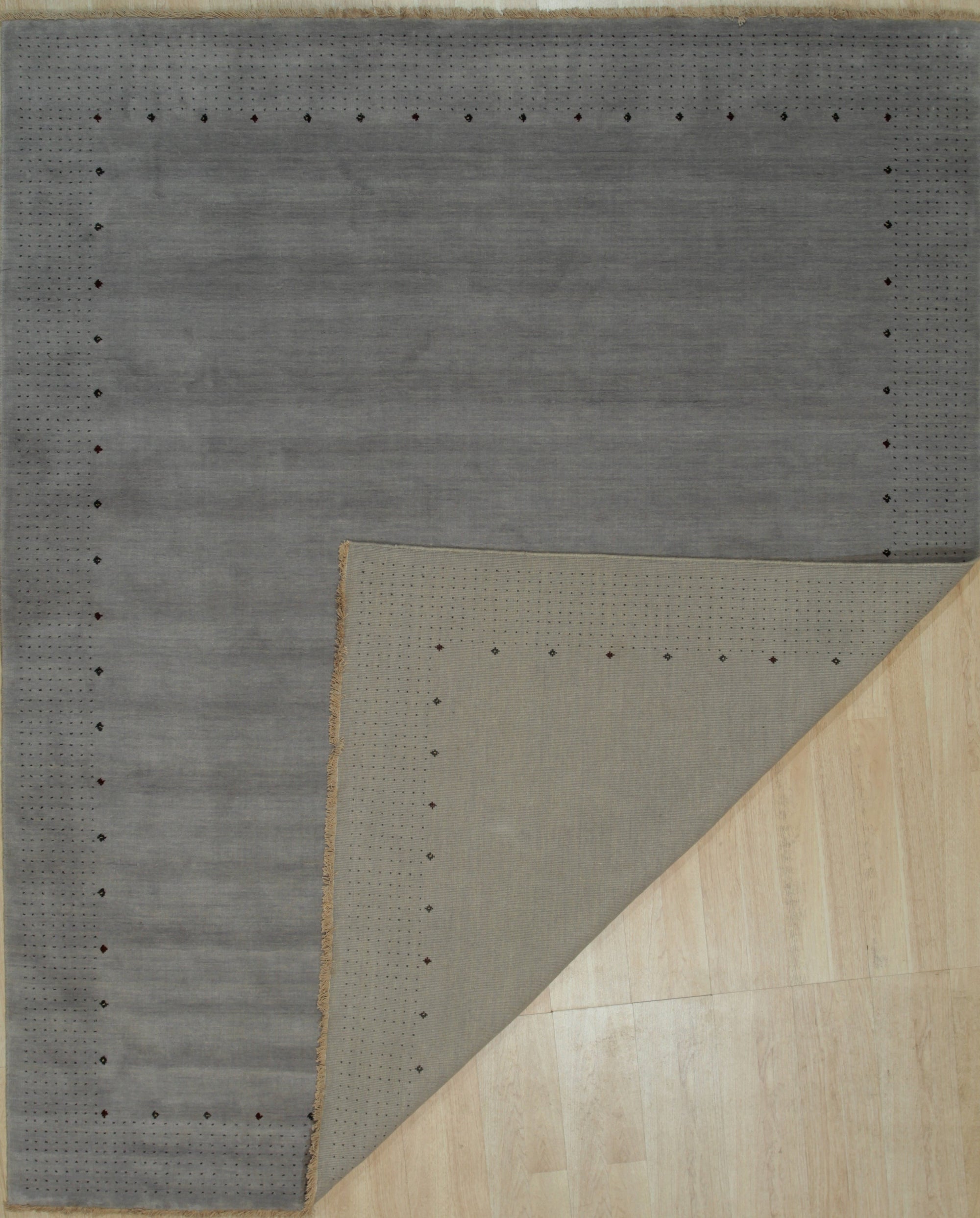 Sophie Alluring Gray Handmade Wool Rug displayed in a modern living space. Gray wool rug features a subtle, geometric pattern adding texture and warmth to the room with neutral-toned furniture.