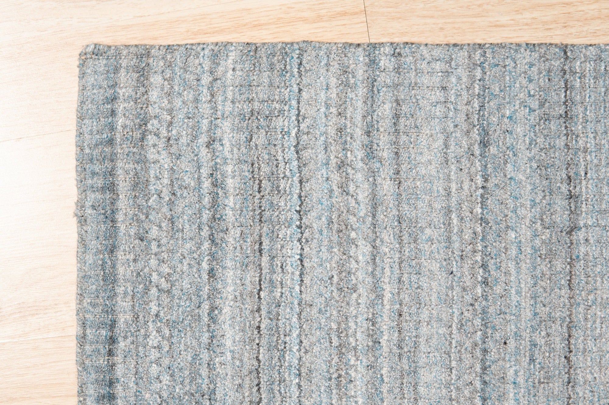 Para Elena Blue Handmade Wool Rug displayed in a brightly lit living room; showcasing its intricate pattern and soft texture against a neutral backdrop.