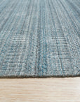 Trara Elena Teal Handmade Wool Rug, its vibrant teal hues and intricate, geometric pattern radiating warmth on a light hardwood floor, complemented by a modern, minimalist setting.