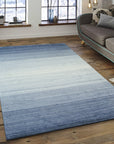 Willow Para Blue Handmade Wool Rug, a calming blend of blues and creams in a textured wool weave, offers a cozy feel underfoot in a brightly lit living space.