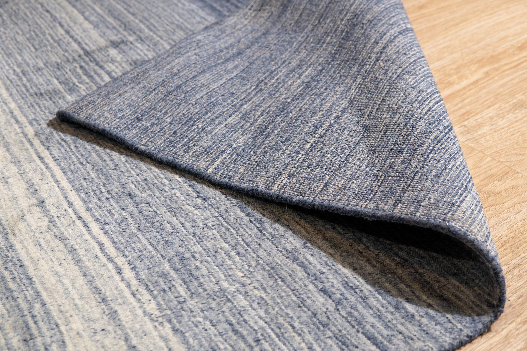 Willow Trara Blue Handmade Wool Rug, a blend of cool blues and subtle creams, presents a textured, hand-woven surface with nuanced variations in tone, hinting at artisanal craftsmanship.