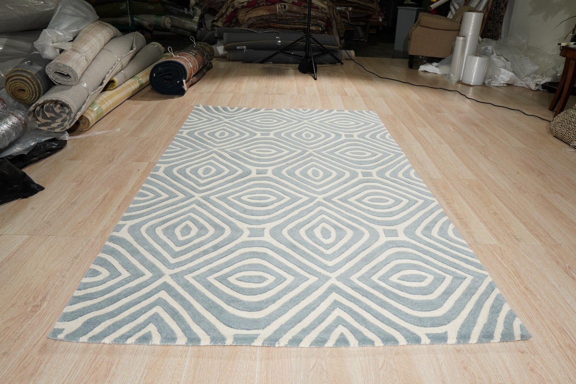 Rhea Stylish Blue Hand Tufted Wool Rug displayed in a bright, minimalist living space, showcasing its textured wool construction and cool blue tones against a light wood floor.