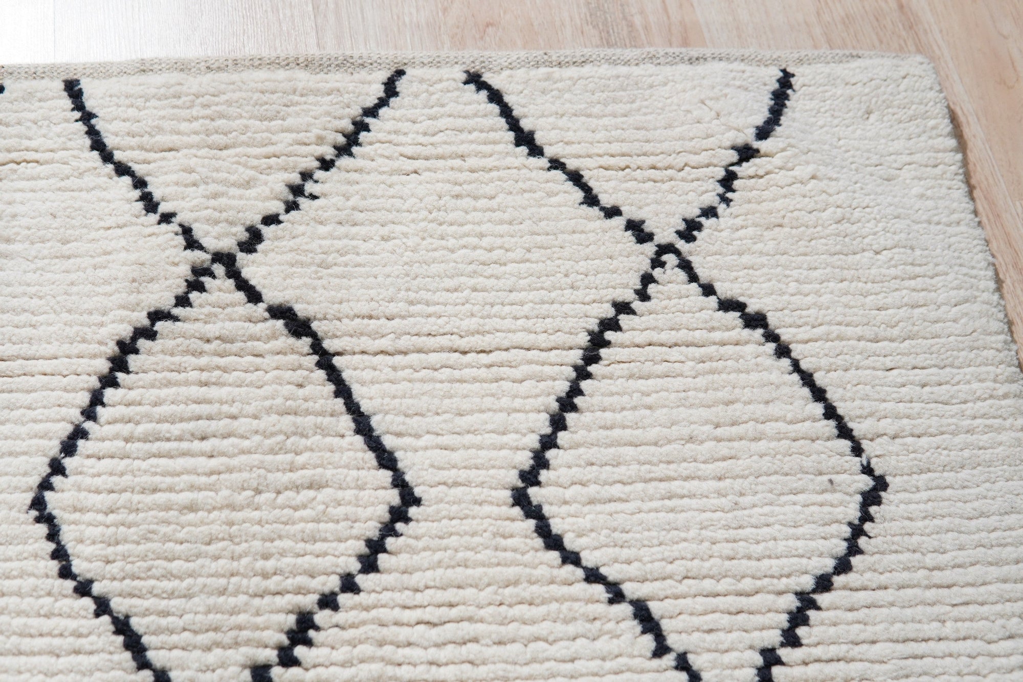 Rhea Diamond Ivory Hand Knotted Wool Rug, its delicate diamond pattern and ivory hues grounding a bright living space with a modern, minimalist aesthetic.