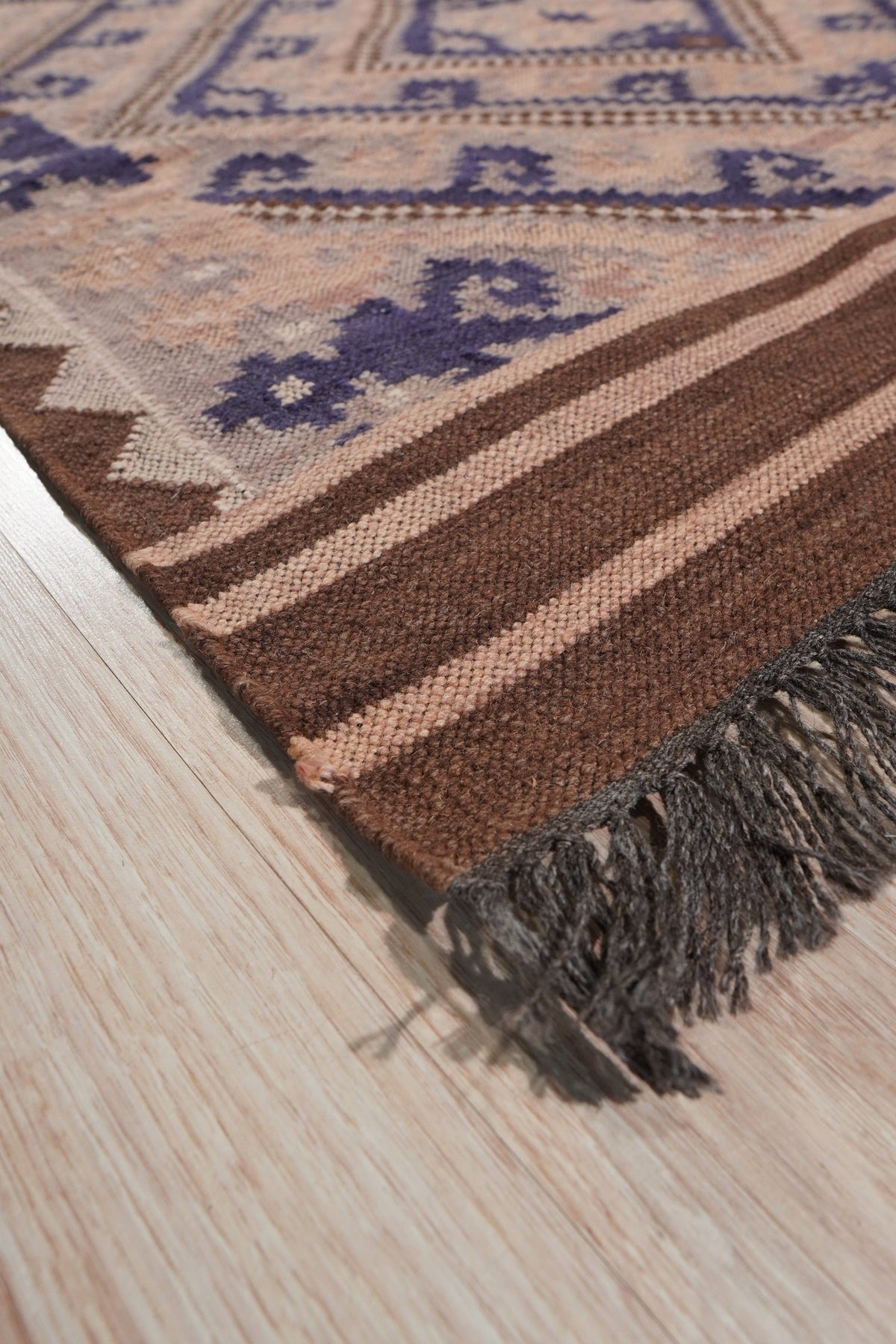 Penelope Jade Brown Flatweave Wool Rug, a blend of warm browns and subtle jade tones in a flatweave construction, displayed in a modern living room setting.