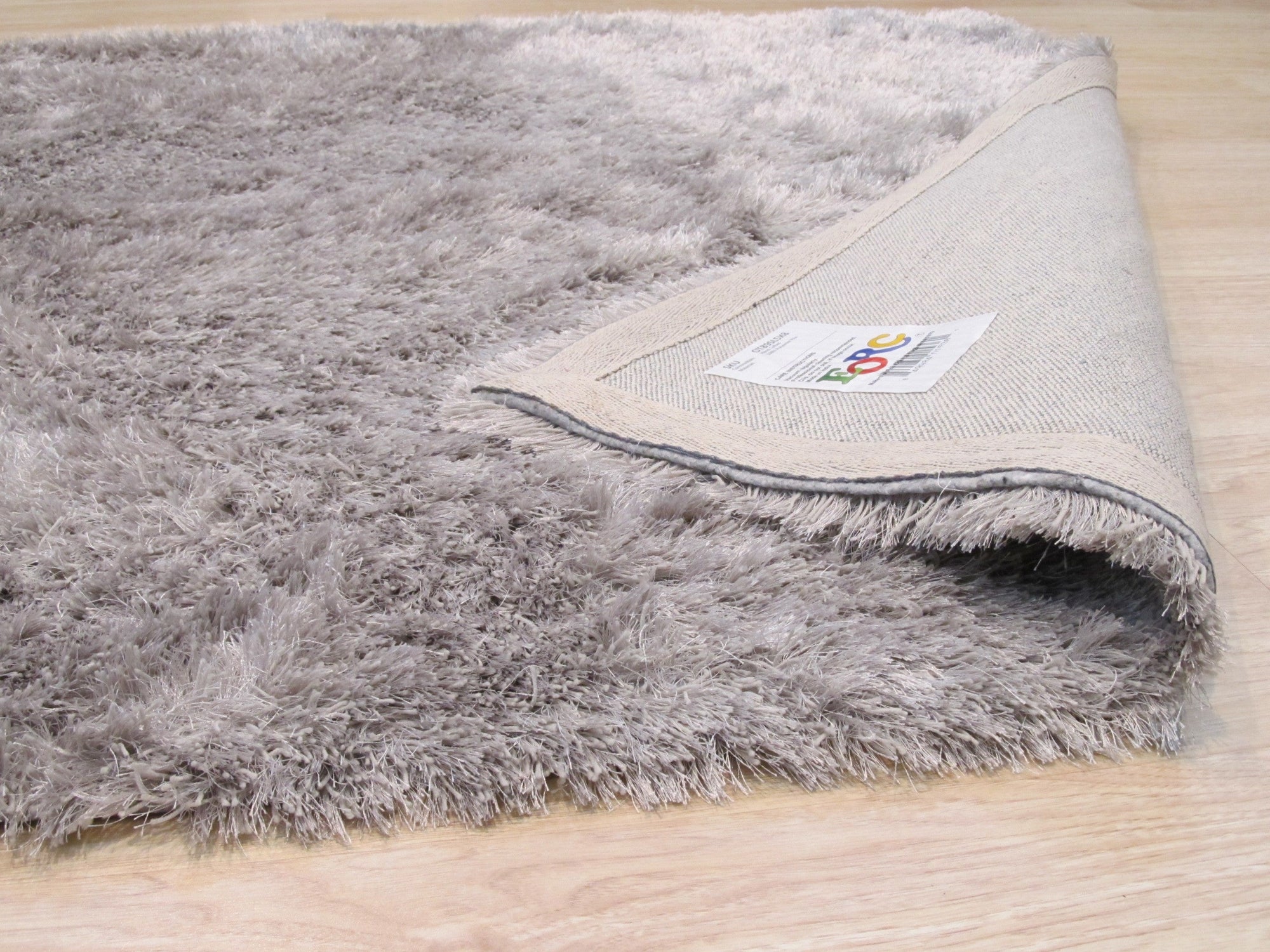 Sophie Timeless Silver Hand Tufted Rug, shimmering with silvery threads, anchors a modern living space. Neutral walls and contemporary furniture highlight the rug&#39;s soft texture and elegant design.