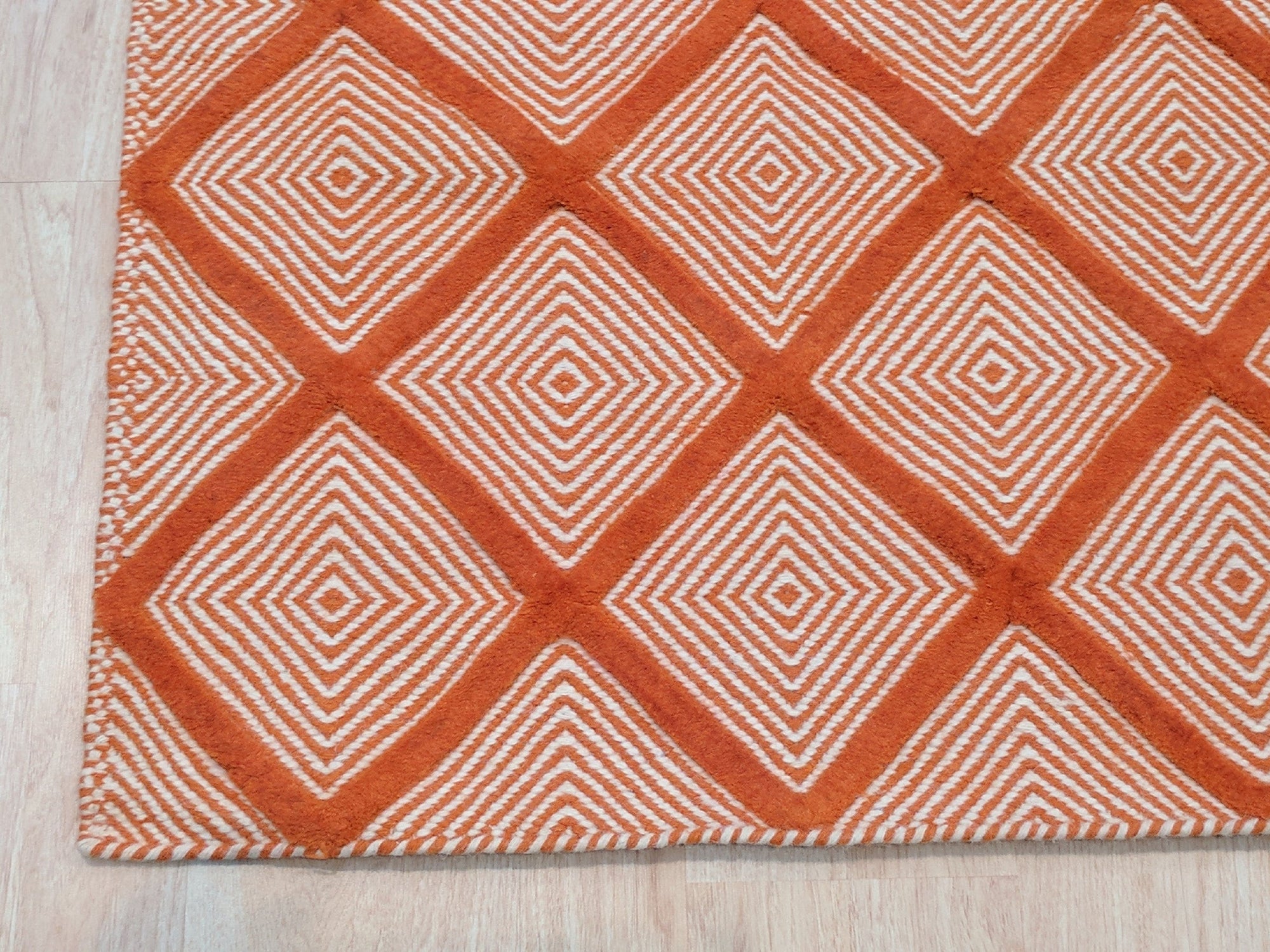 Refined Luxurious Orange Handmade Wool Rug, rich ochre tones swirling in a dense wool pile, hints of geometric pattern suggesting a timeless, handcrafted artistry.