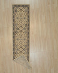 Ivory and slate blue Oushak wool runner rug with a corner folded back to show the hand knotted pile and backing