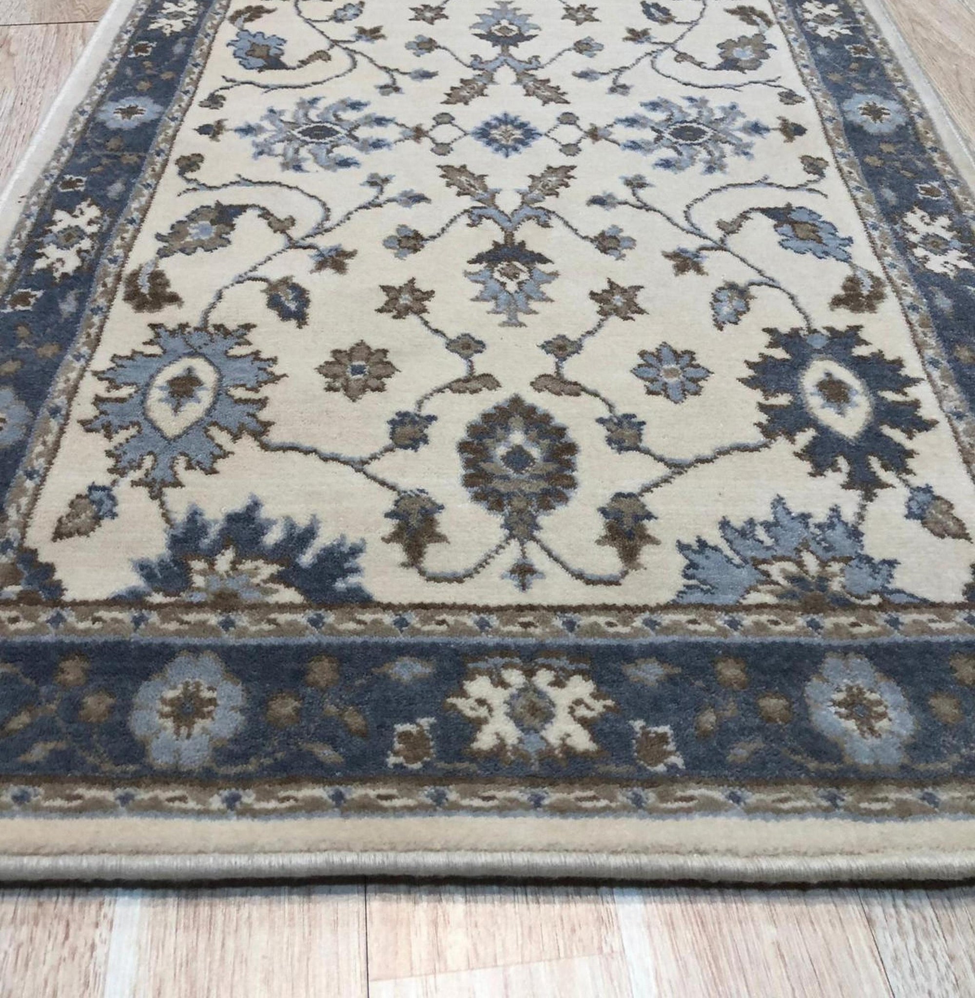 Detail of the blue, brown and cream palmette and vine pattern on the Charming Oushak ivory wool runner rug