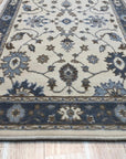 Detail of the blue, brown and cream palmette and vine pattern on the Charming Oushak ivory wool runner rug