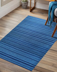 Trara Penelope Blue Flatweave Wool Rug, sprawling across a sun-drenched living room; its cool blue tones and flatweave texture grounding the modern space.