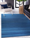 Trara Penelope Blue Flatweave Wool Rug, its intricate geometric pattern in varying shades of blue creating a dynamic yet calming atmosphere in a bright living space.