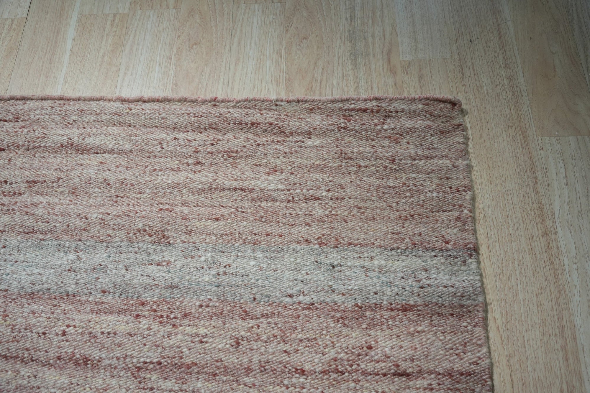 Rhea Selene Pink Flatweave Wool Rug displayed, showcasing its subtle pink hues and flatweave construction.