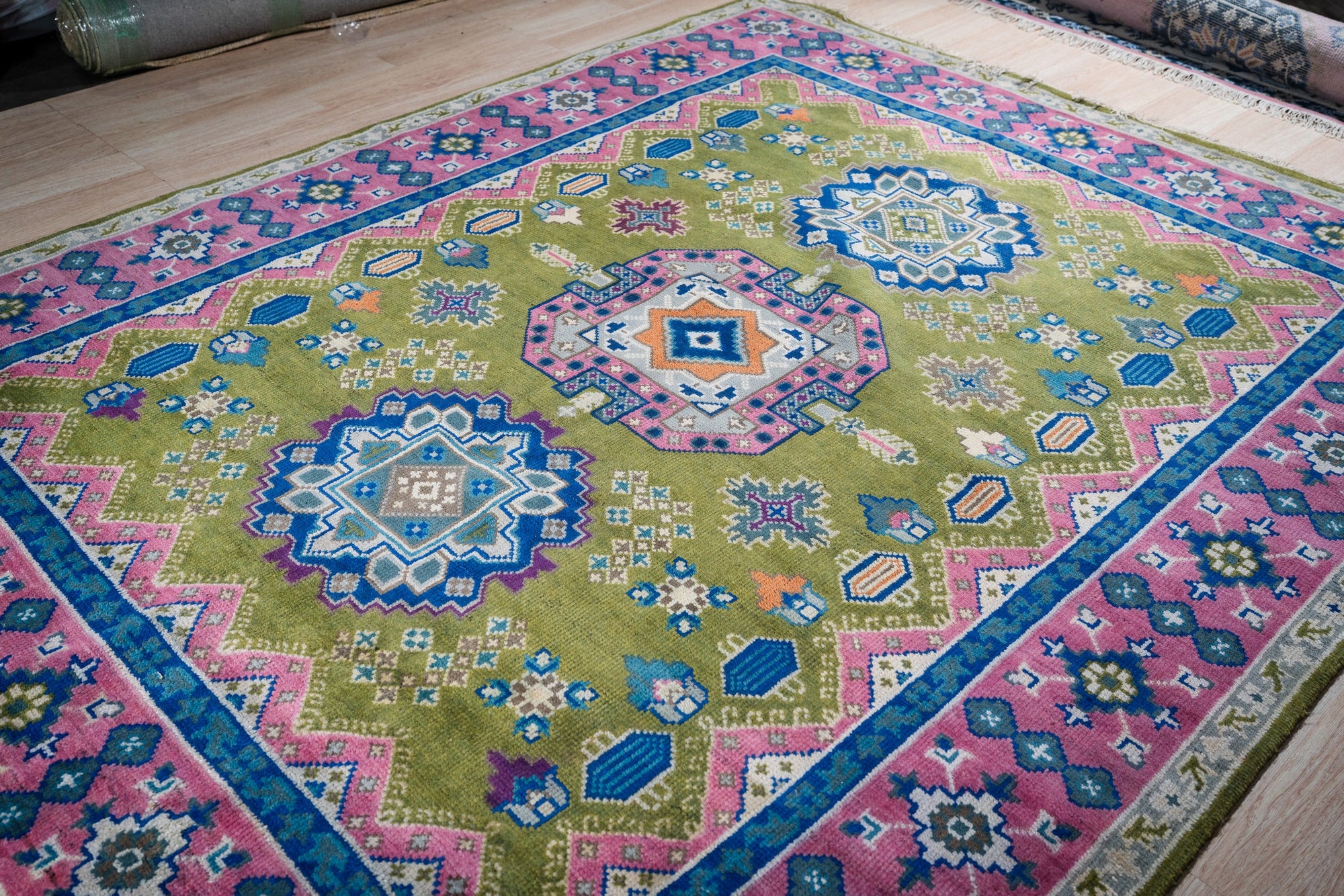 Green and fuchsia Kazak hand-knotted rug, angled view showing medallions