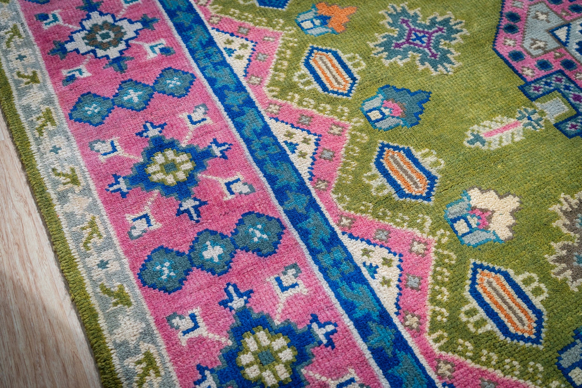 Green and fuchsia Kazak rug border and field close-up