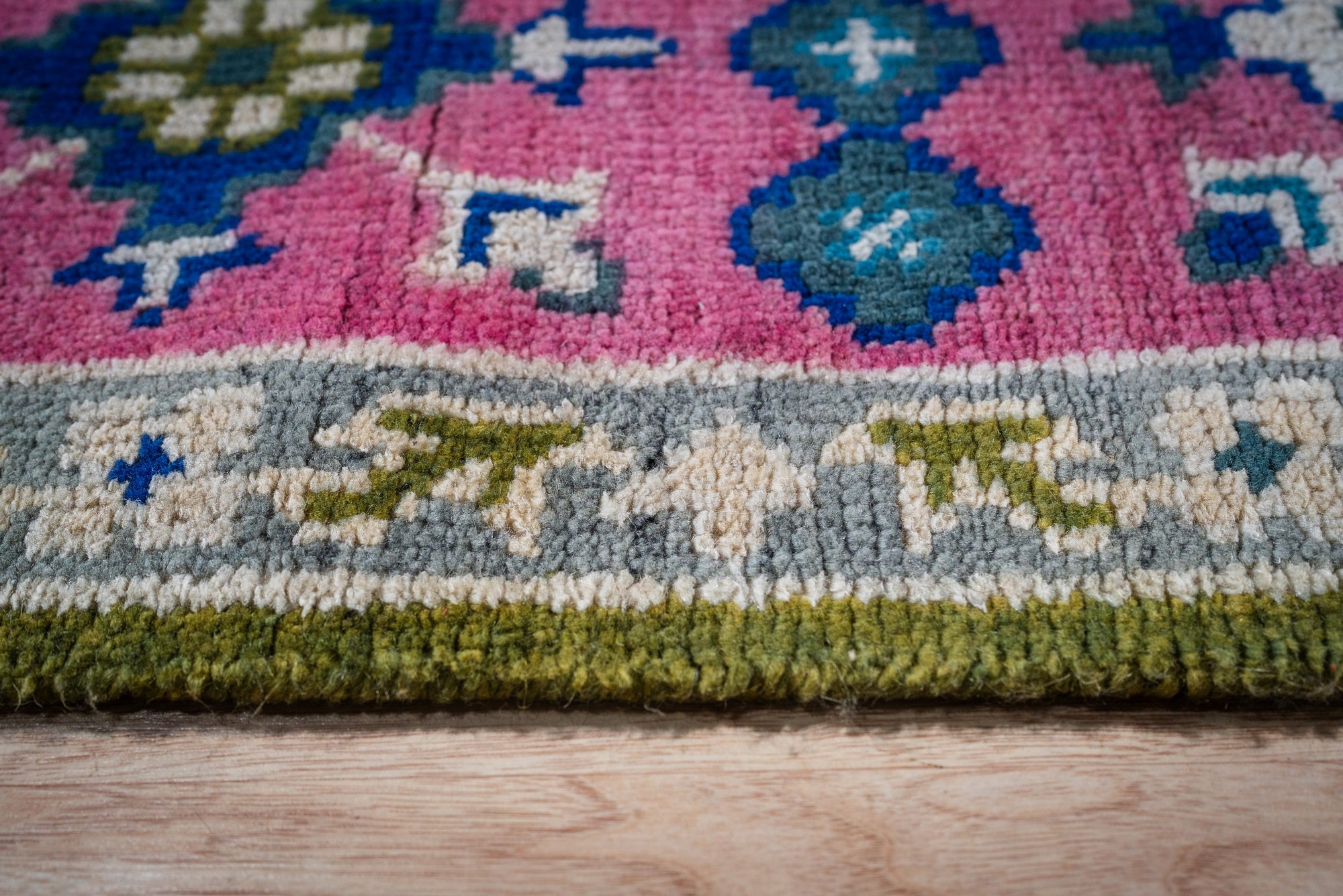 Green and fuchsia Kazak rug border close-up