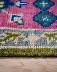 Green and fuchsia Kazak rug border close-up