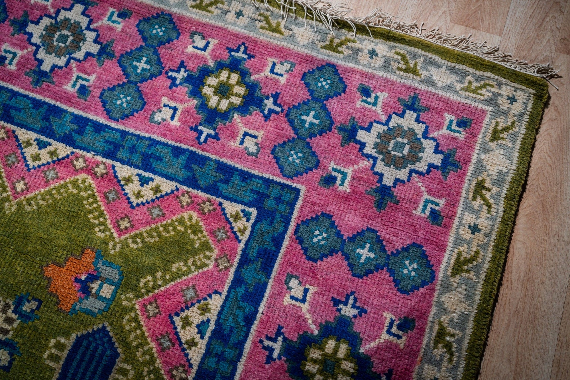 Green and fuchsia Kazak rug corner and fringe detail