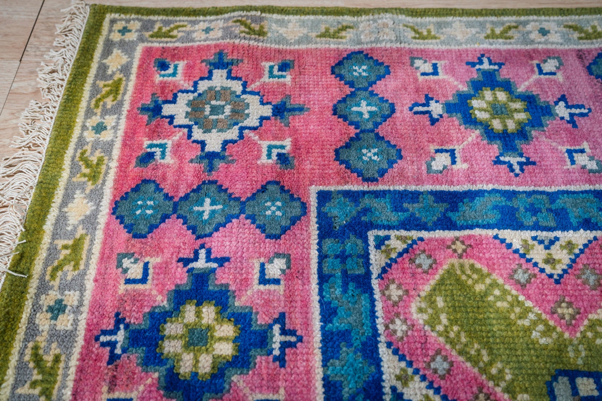 Green and fuchsia Kazak rug corner pattern detail