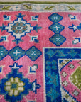 Green and fuchsia Kazak rug corner pattern detail
