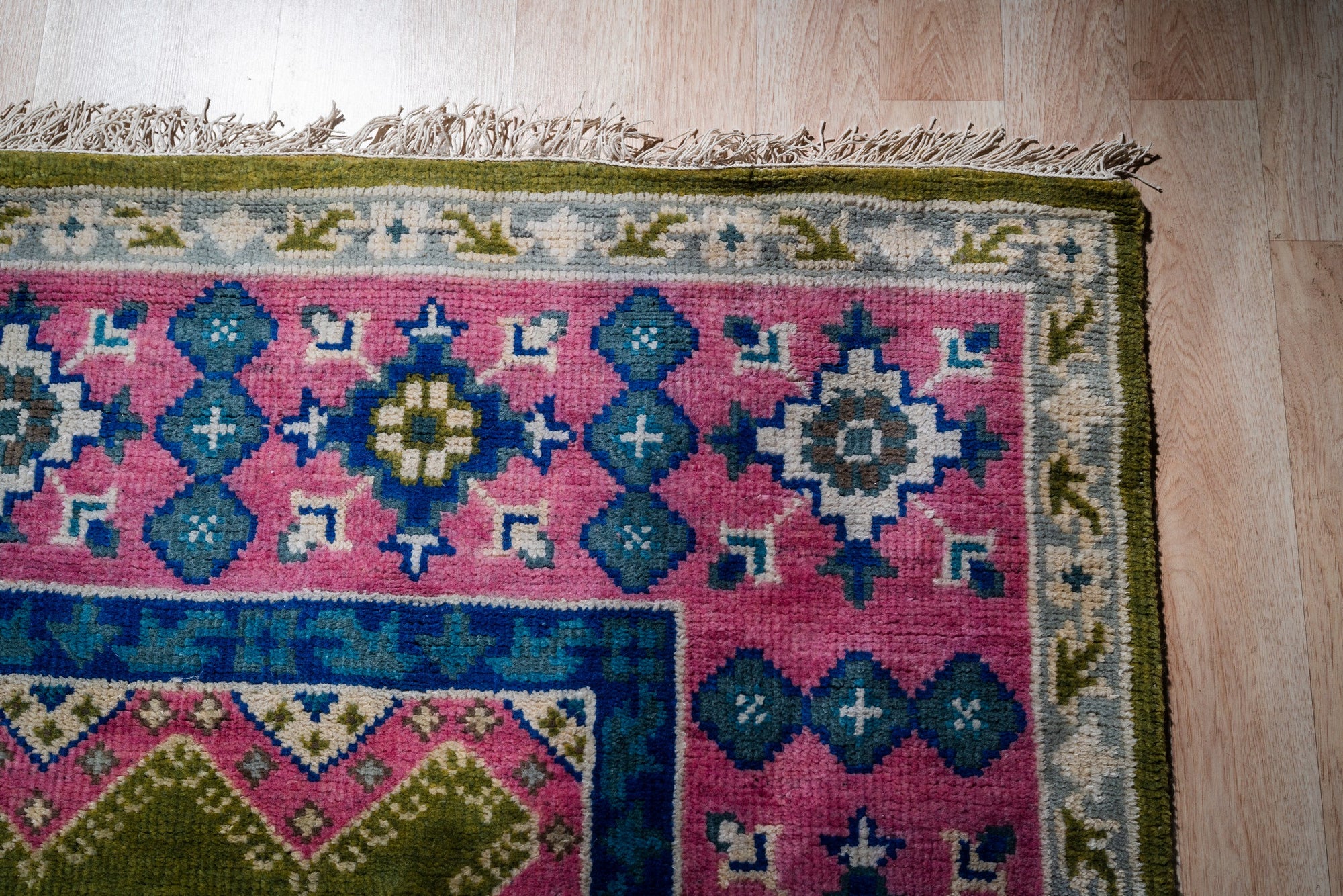 Green and fuchsia Kazak rug corner detail