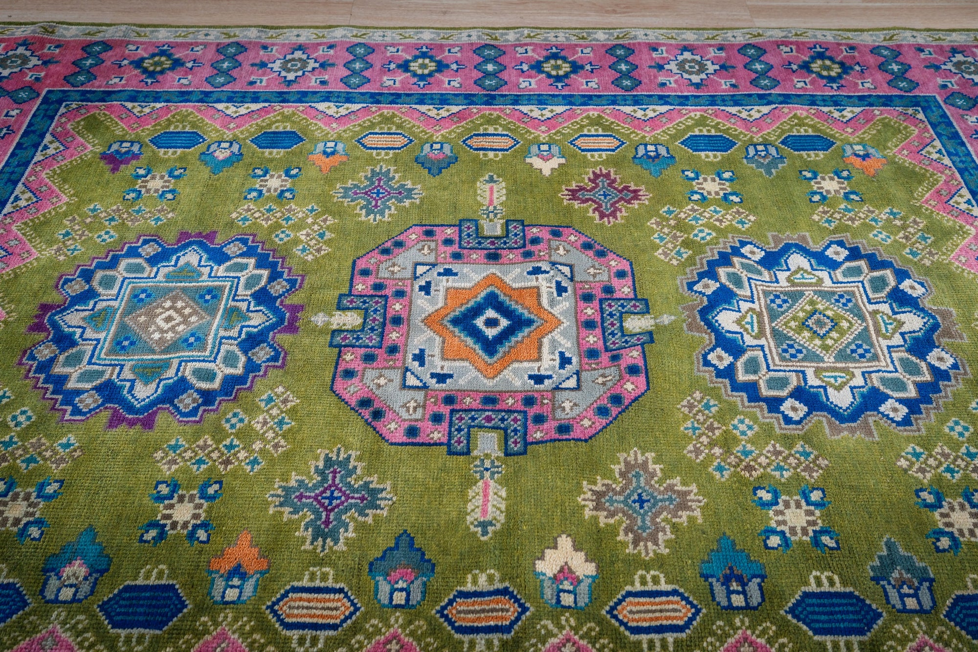 Green and fuchsia Kazak rug top-down three-medallion detail