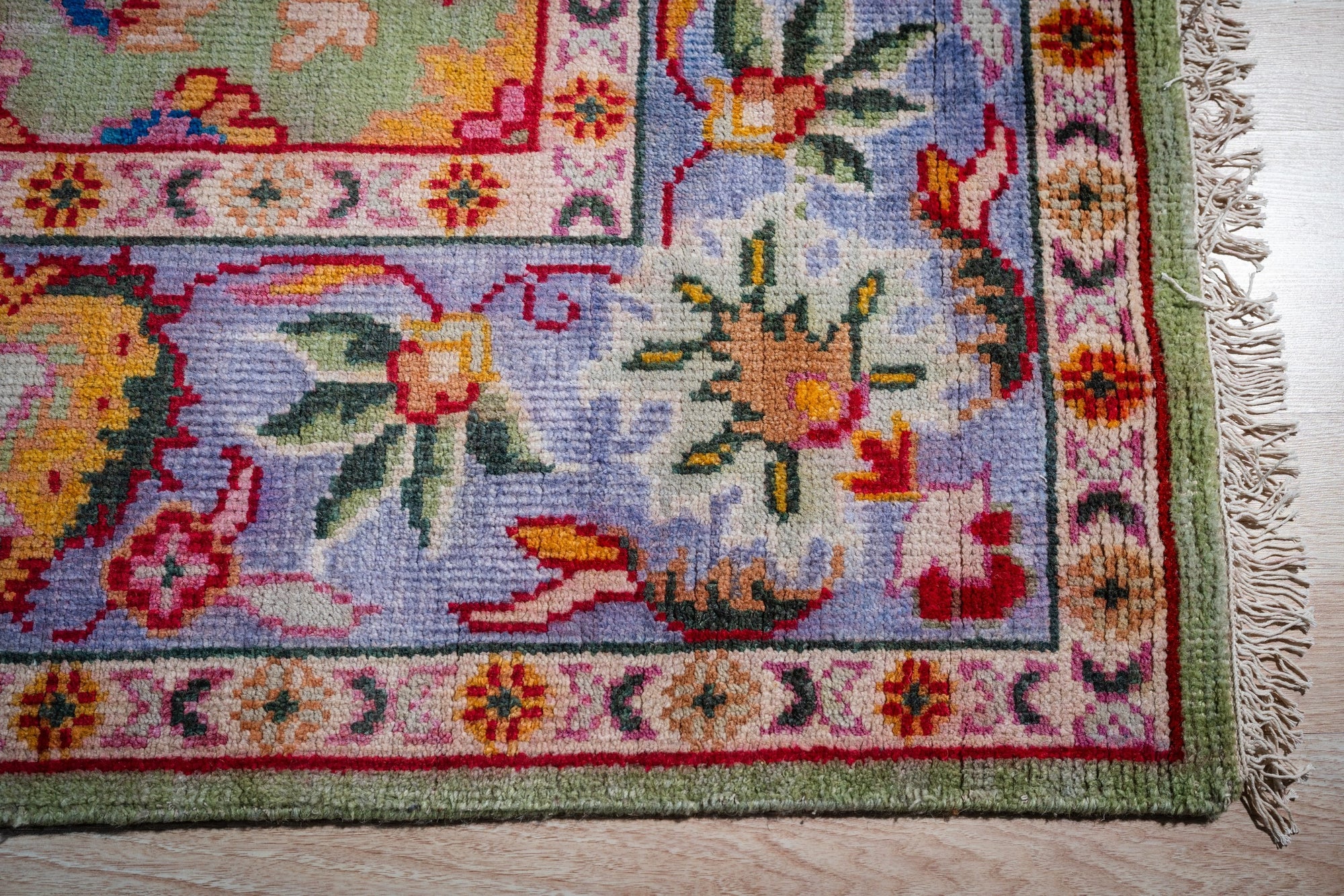 Light green Oushak rug corner and periwinkle border detail