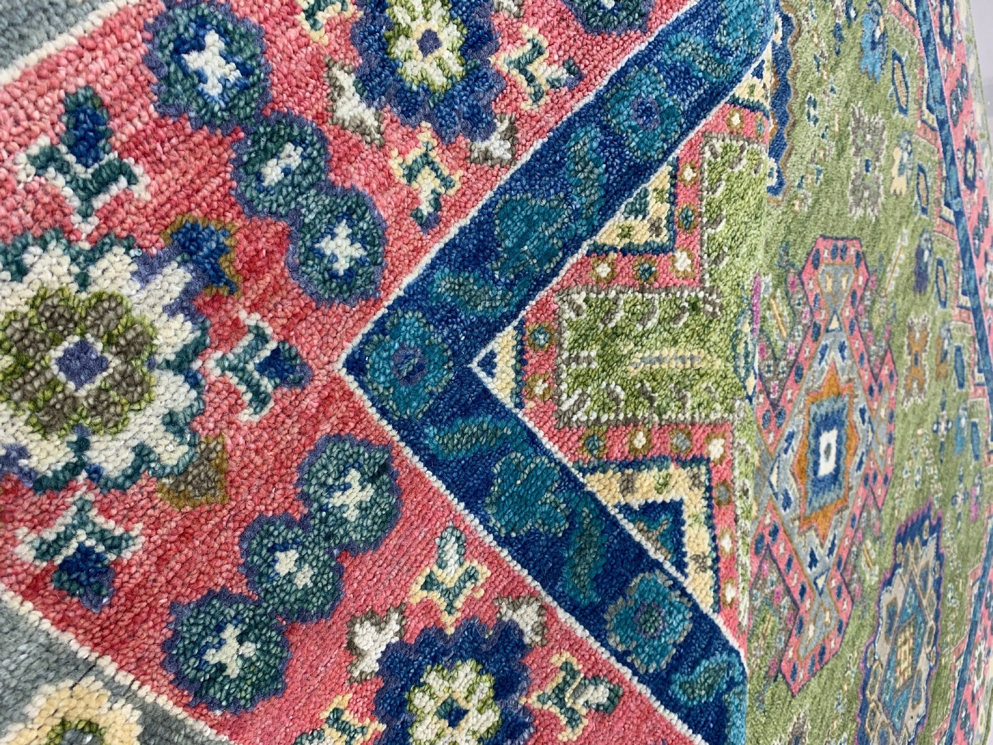 High-pile rug featuring bold geometric patterns in contrasting pink, royal blue, and olive green.