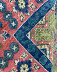 High-pile rug featuring bold geometric patterns in contrasting pink, royal blue, and olive green.