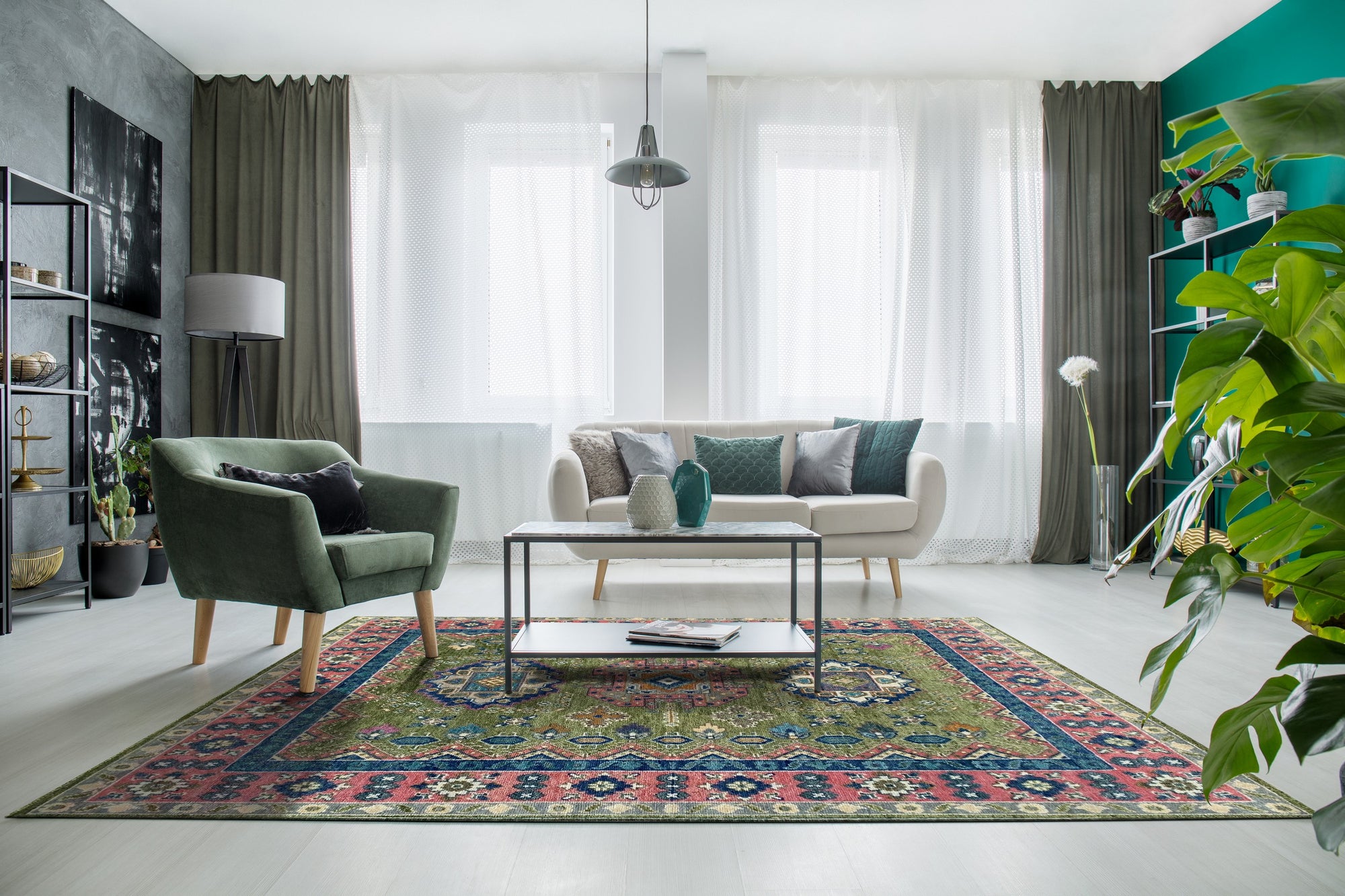 A traditional green, blue, and pink patterned rug anchors a living room with a cream sofa and green chair.