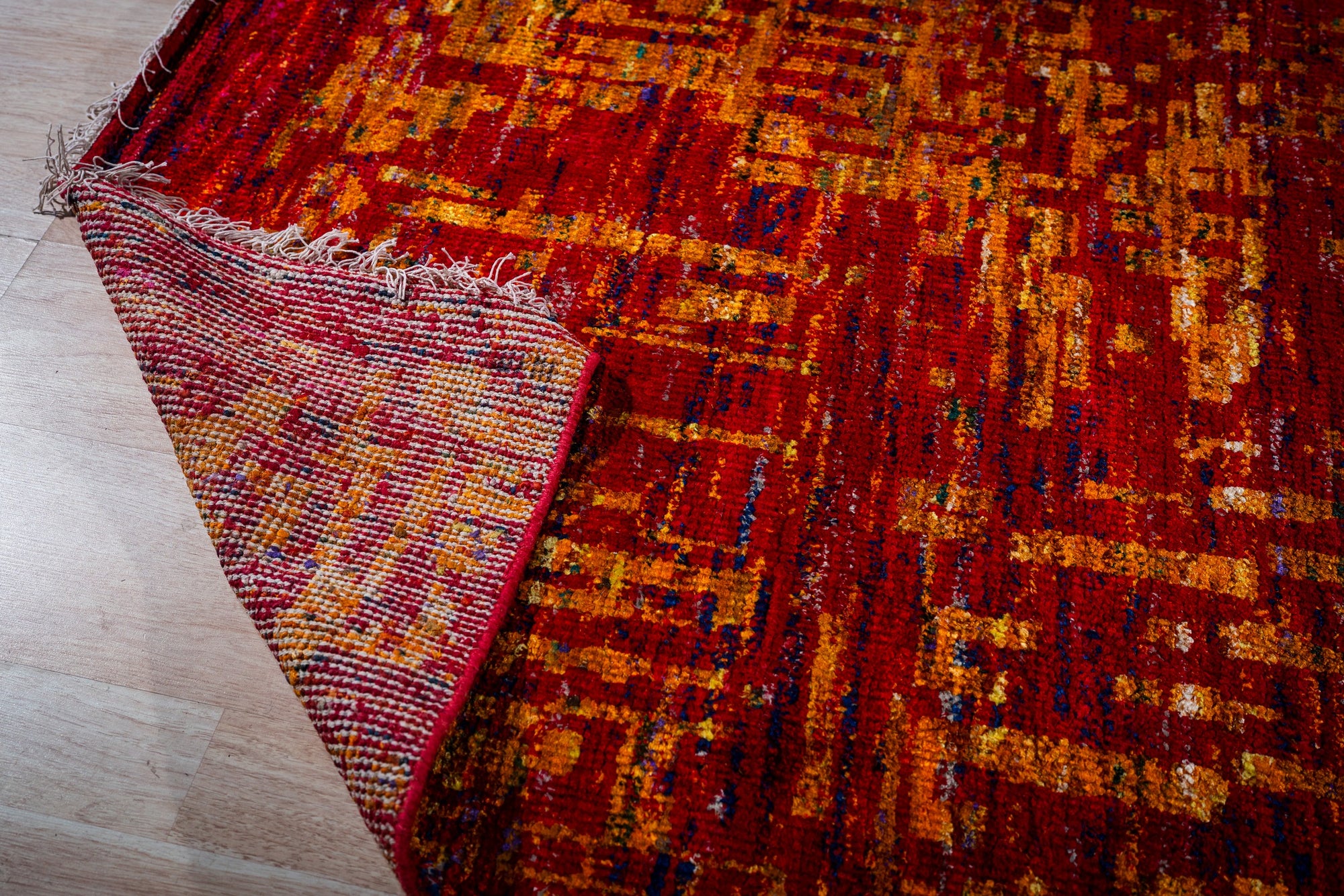 Sari-silk red abstract Anand rug corner folded showing the back