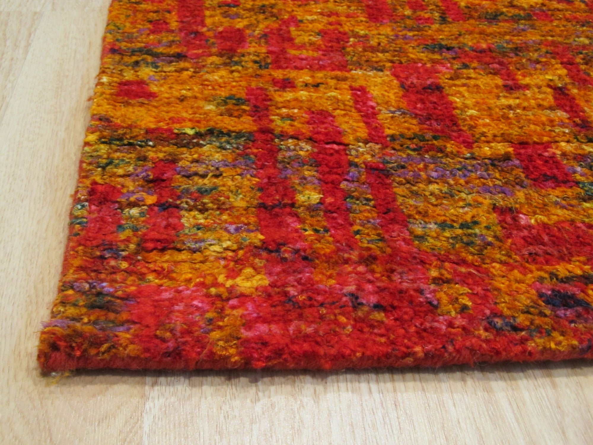 Anand red sari-silk rug corner detail showing abstract gold and orange pattern