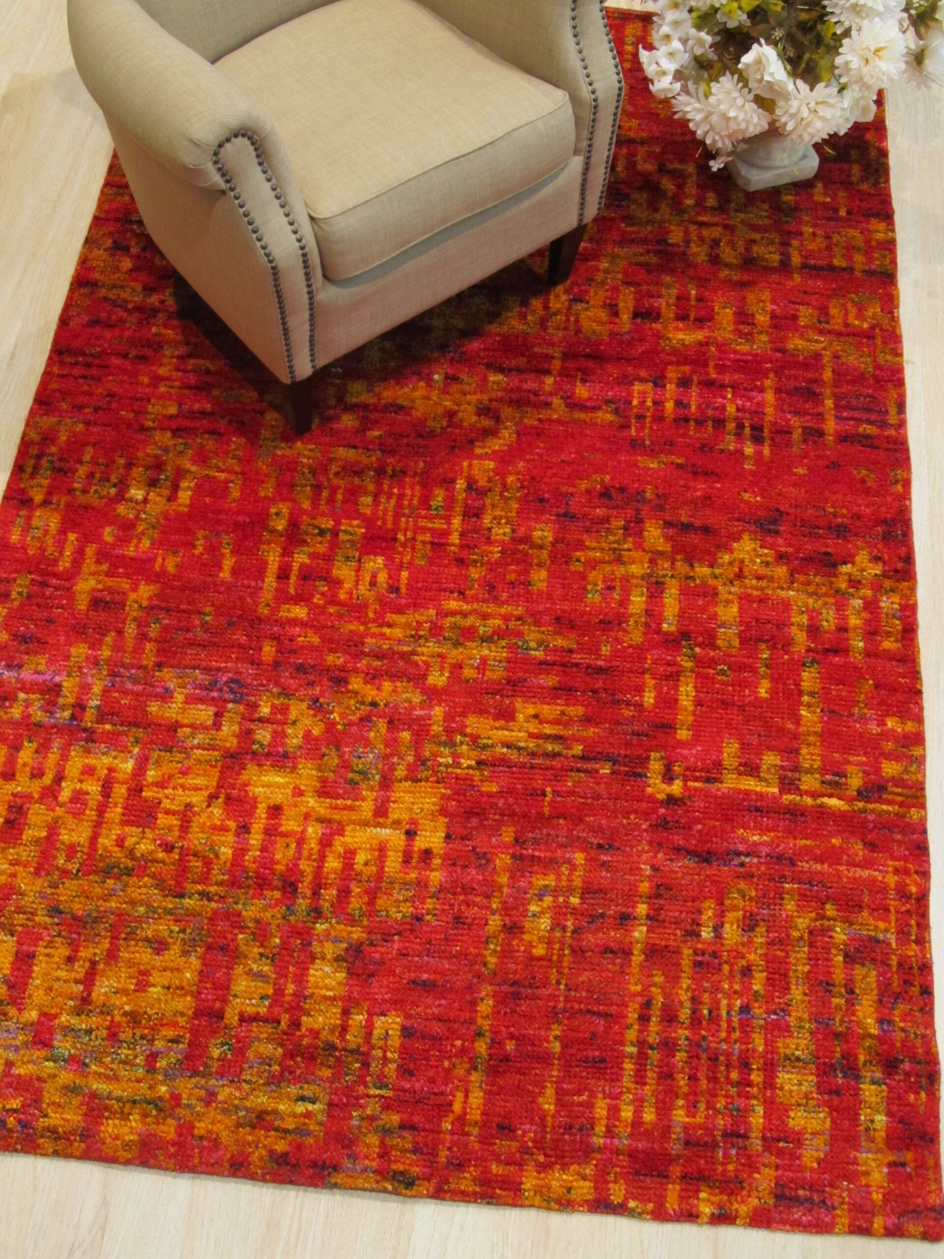 Red sari-silk Anand rug styled in a room with an armchair
