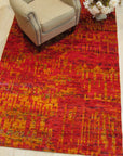 Red sari-silk Anand rug styled in a room with an armchair