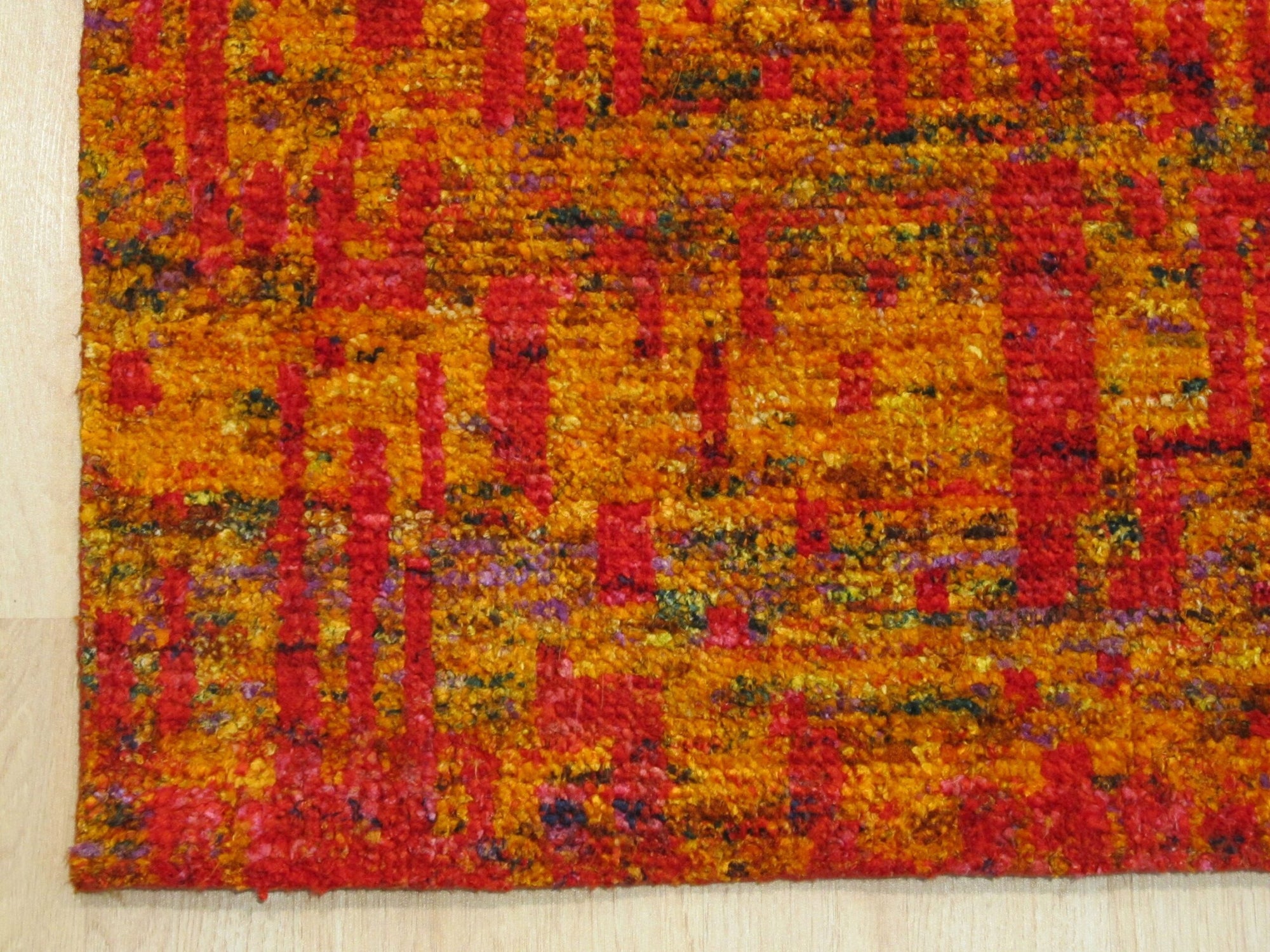 Close-up of Anand rug recycled sari-silk pile texture in red and gold