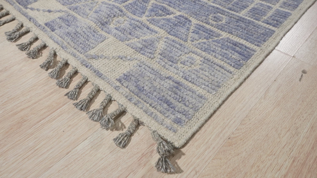 Elegant Marrakech Blue Hand-Knotted Wool Rug, with vibrant blue and cream geometric patterns, enriching a warmly lit living space.