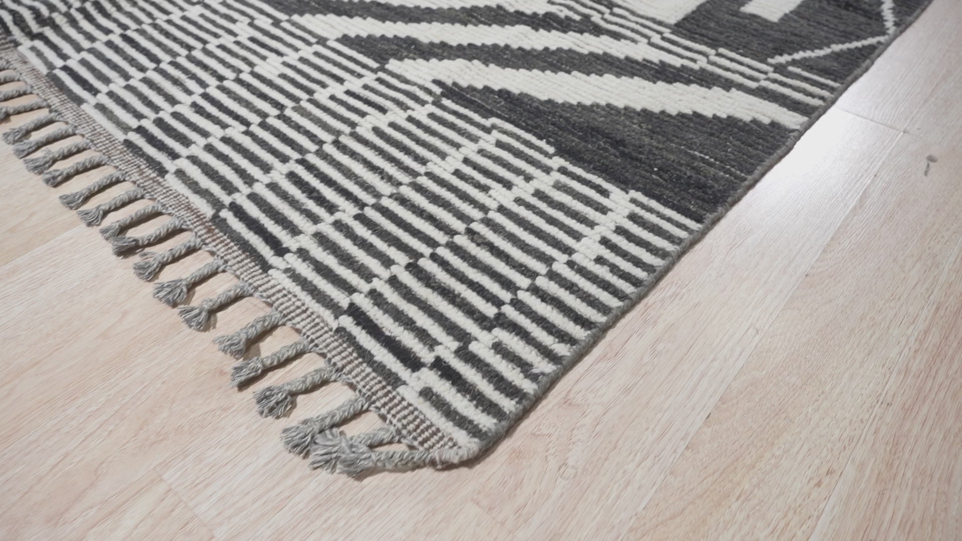 Okay, I analyzed the video and will generate alt text based on the image position being 10.
 
 **Marrakech Essence Black Rug graces a modern living room, its intricate black patterns contrasting beautifully against a light wooden floor. The rug anchors a seating area with a neutral sofa and minimalist decor, highlighting its artisanal construction and adding a touch of Moroccan-inspired elegance to the space.**