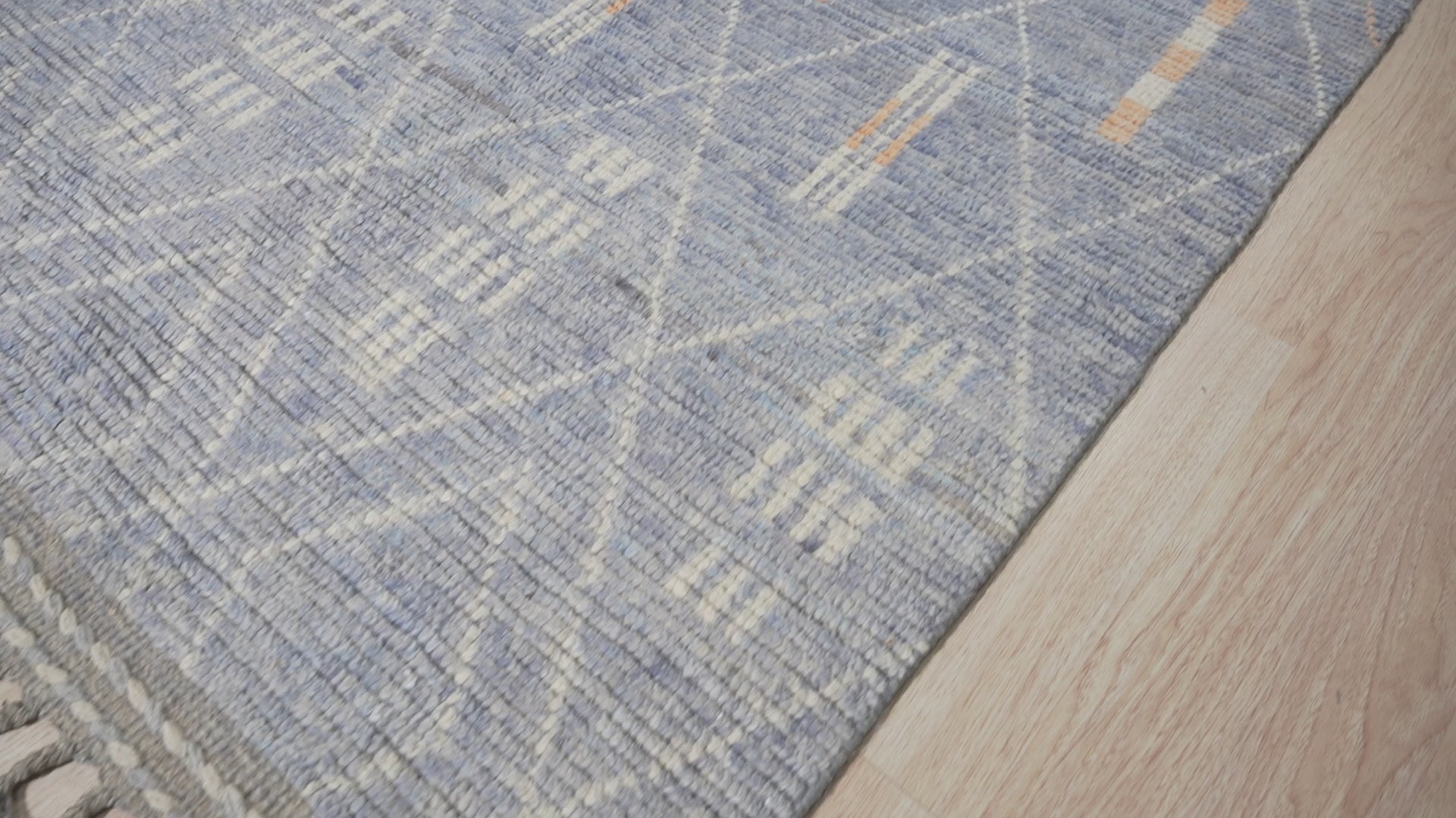 Graceful Marrakech Blue Hand-Knotted Wool Rug, displaying intricate Moroccan-inspired patterns in vibrant blues and creams, softening a modern living room space.