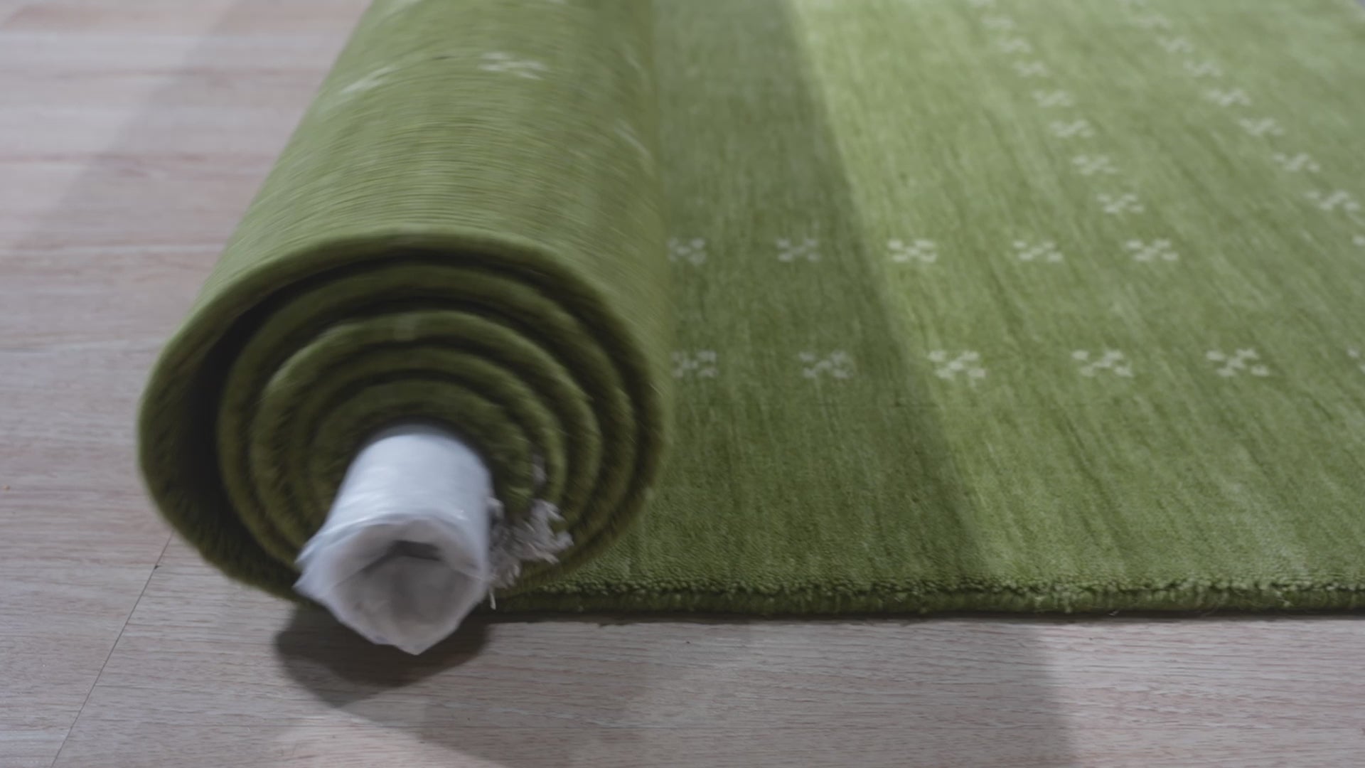 Jasmine Alluring Olive Handmade Wool Rug, a textural haven in earthy olive tones, underfoot in a warmly lit room.