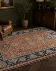 Rust Oushak floral rug styled in a green library with a leather chair